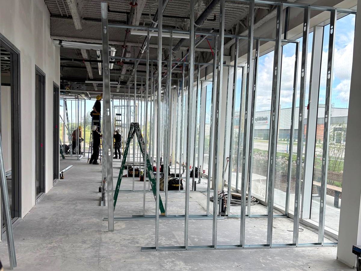 Stouffville Dental Studio under construction at the Stouffville Medical Arts building — steel framing and full-height glass exterior walls visible, with trades on site