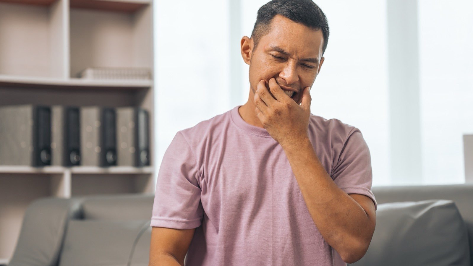 A man holding his jaw with an expression of pain from severe toothache